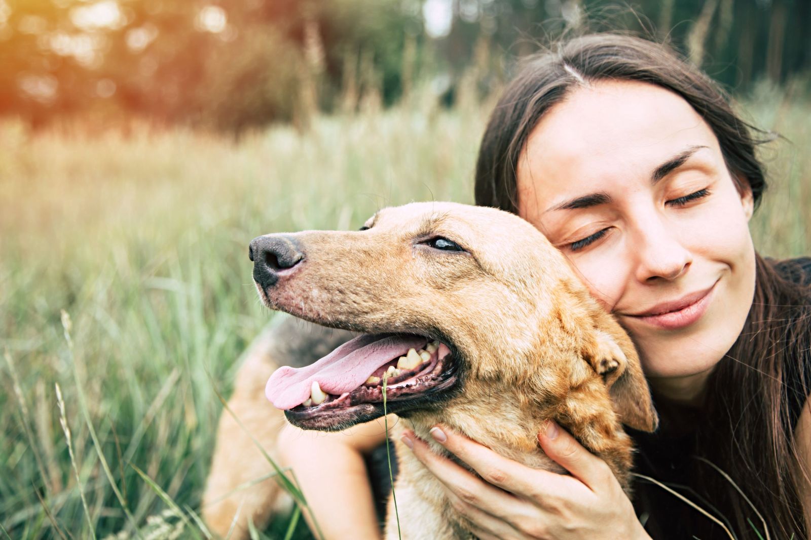 A woman cuddling her dog in long grass